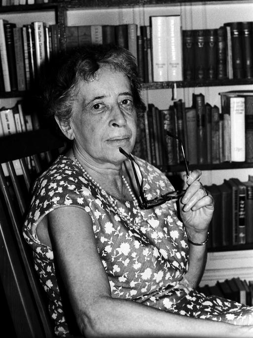 Denkerin vor Büchern als Symbol für Philosophie, Wissen und Reflexion.
